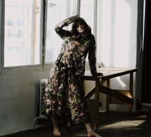 trendy young lady leaning on table placed near wall in room